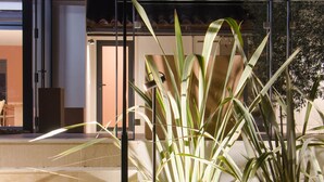 A modern building with a glass entrance, steps leading up to the door, and a planter with tall plants in front. - Charming and elegant villa (Tarascon)