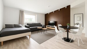 Een moderne hotelkamer met een bed, een bank, een televisie, een eettafel en stoelen.