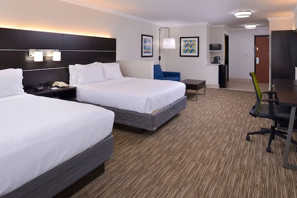 Una habitación de hotel con dos camas, un escritorio, una silla y una mesita.