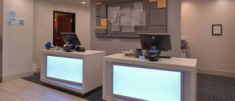 A hotel reception area with two reception desks, each equipped with a computer and a phone.