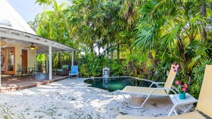 A covered patio with a pool, surrounded by lush tropical vegetation.