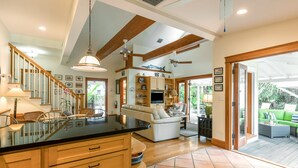 A spacious kitchen with wooden cabinets, a black countertop, and a dining area with chairs and a table.