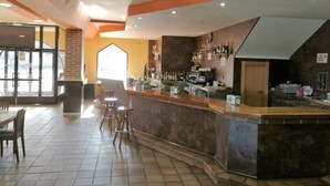 Zona de bar con taburetes, una barra y estanterías con botellas.
