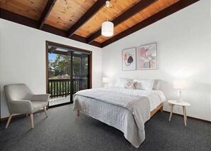 Une chambre à coucher avec un lit, une chaise, une petite table et des œuvres d’art accrochées au mur.