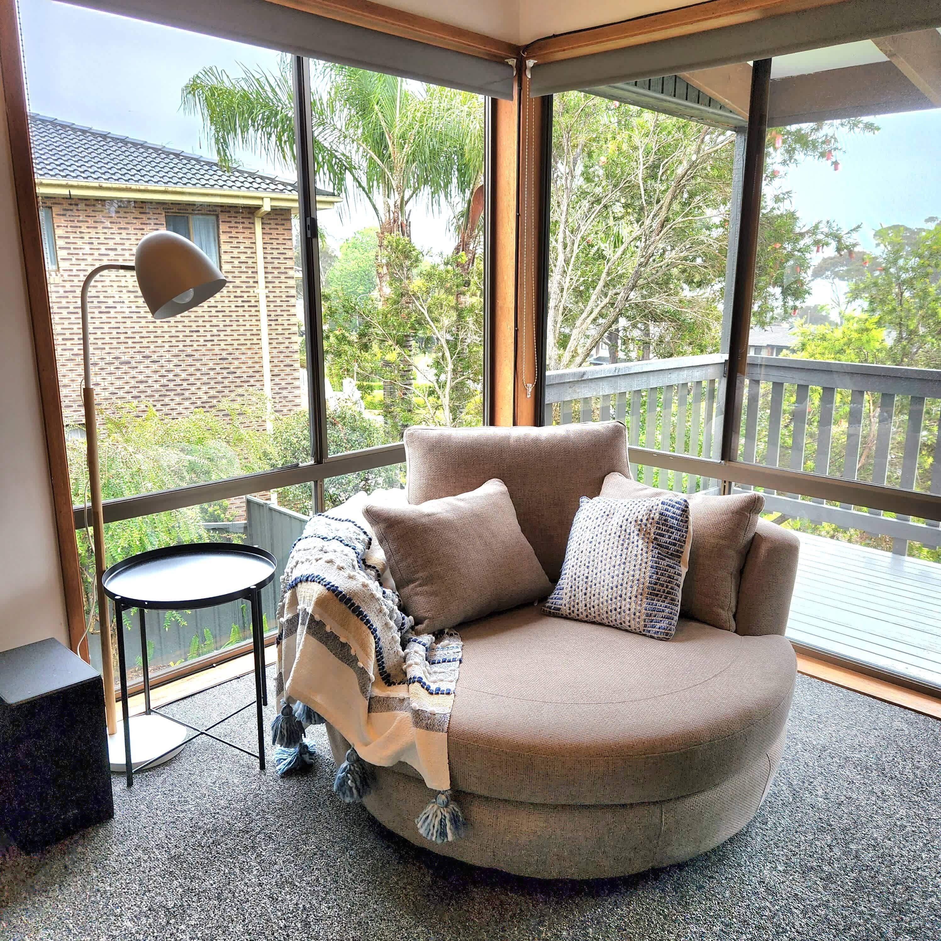 A room with a curved sofa, a small round table, and a floor lamp.