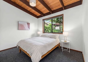 A bedroom with a bed, a window, a bedside table, and a lamp.