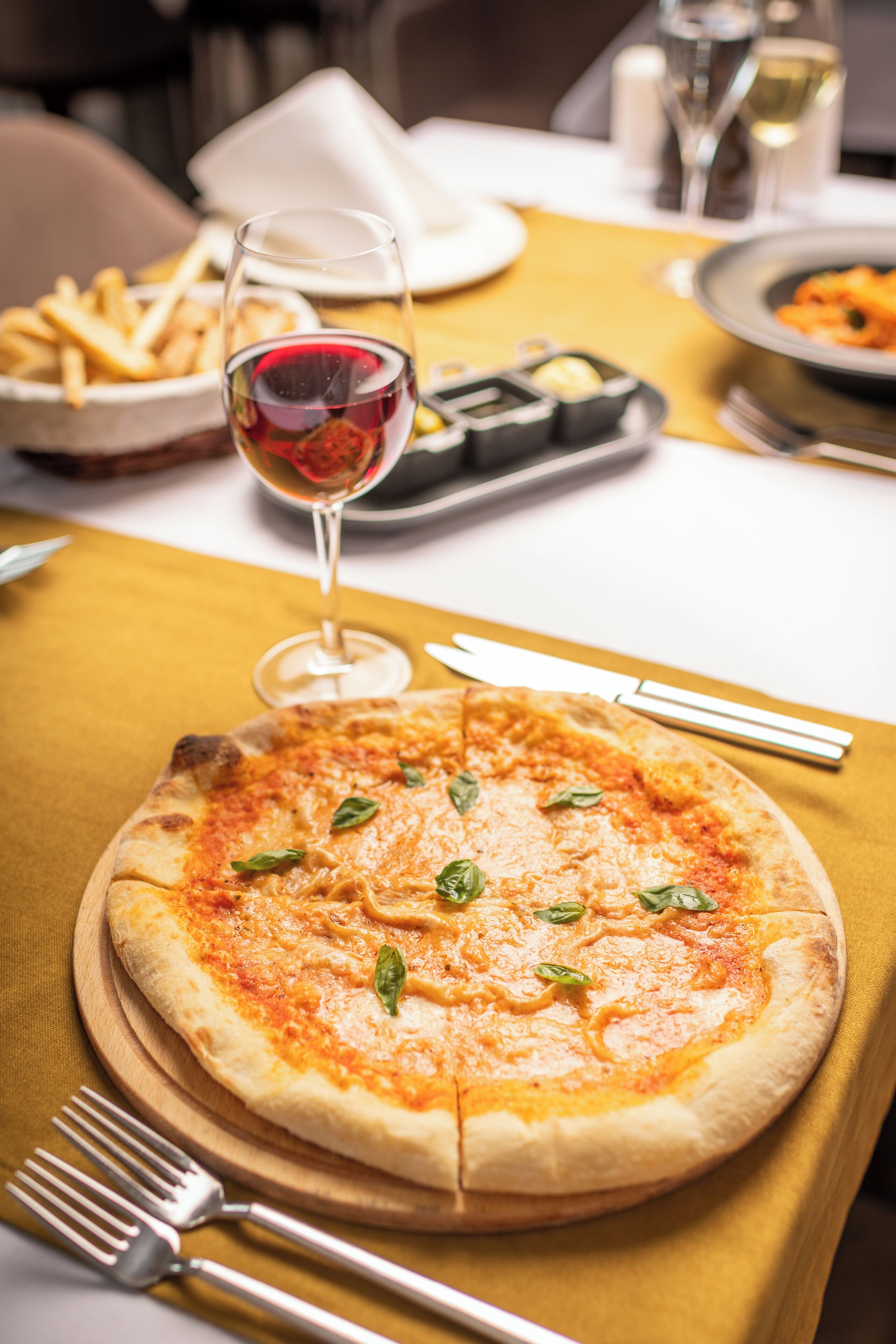 A pizza on a wooden board with a fork and knife beside it.