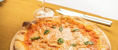 A pizza on a wooden board with a fork and knife beside it.