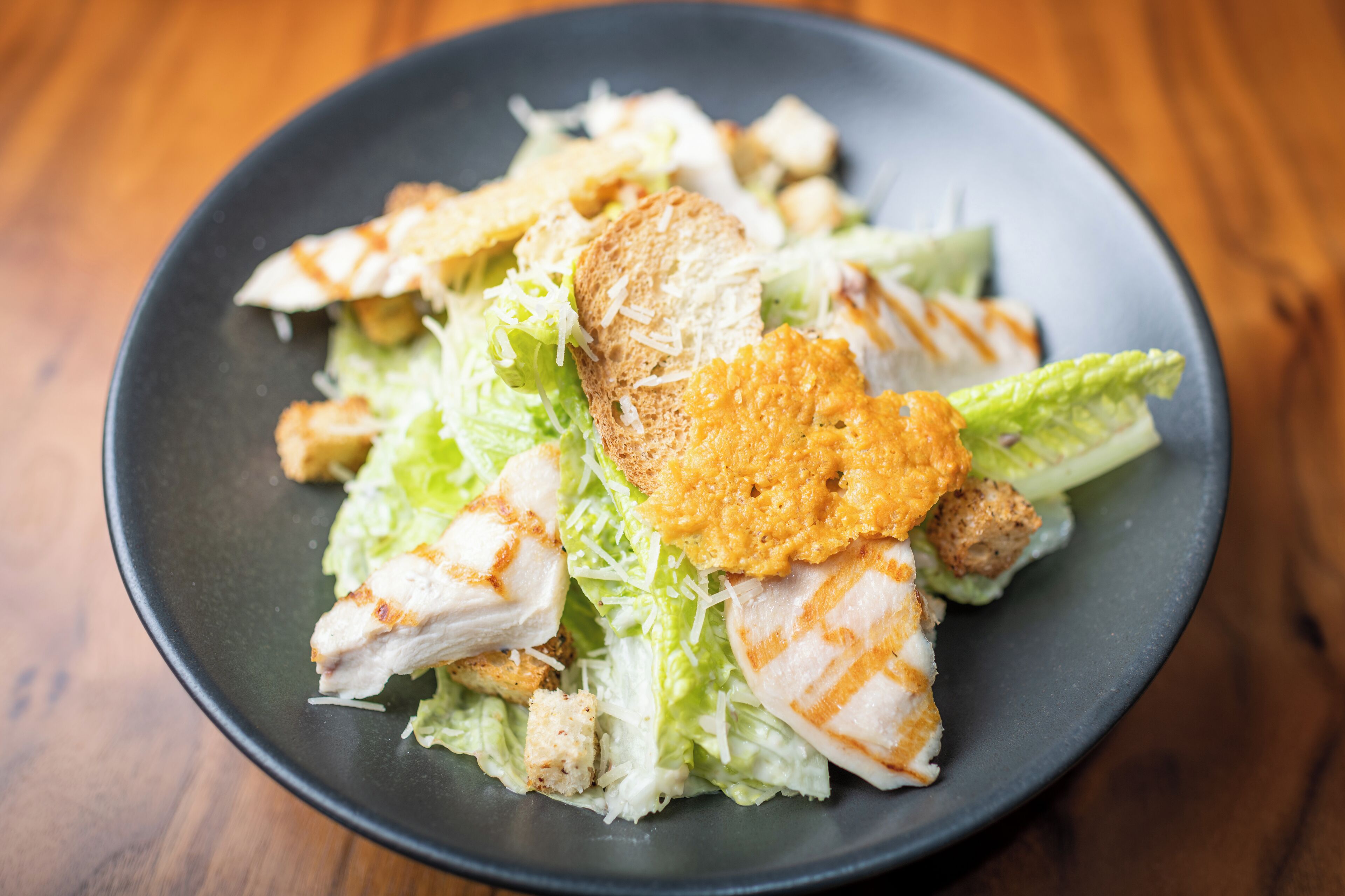 A plate of food with grilled chicken, croutons, and shredded lettuce.