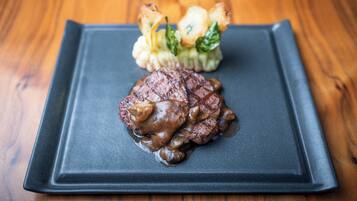 Een vierkant bord met een steak en groenten op een houten tafel.