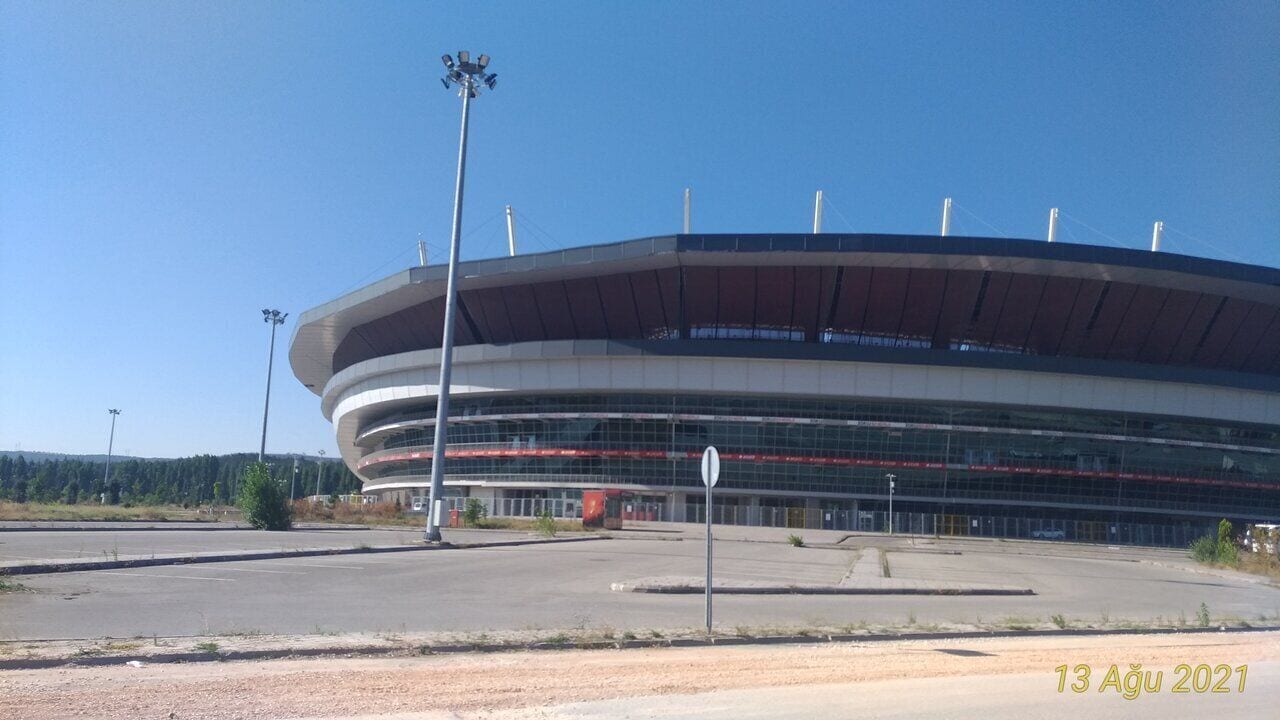 Een groot, modern stadion met een gebogen dak en meerdere niveaus.
