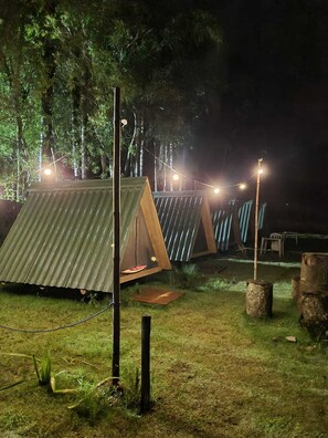 A campsite at night with tents and string lights. - Family Camp (Suzano)