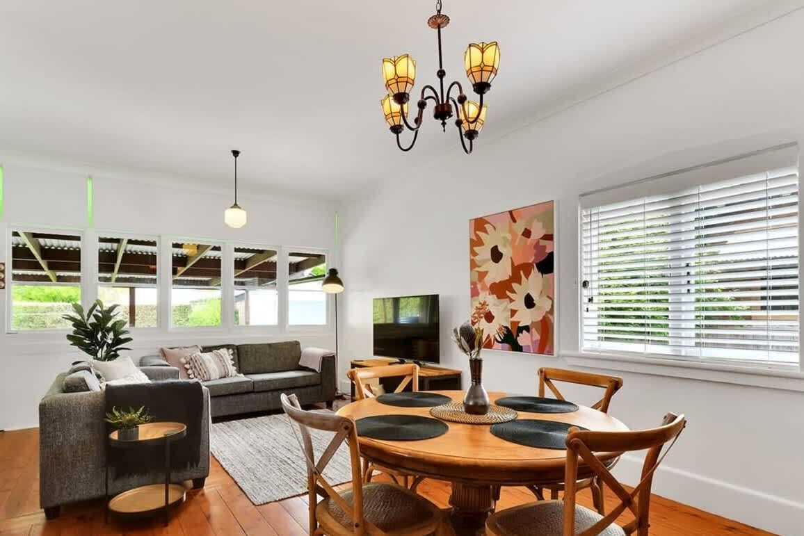 A spacious living area with a dining table, sofas, and a television.