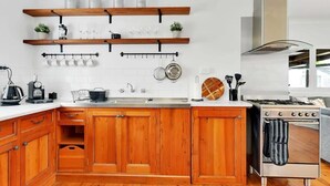 Uma cozinha com armários de madeira, um fogão de aço inoxidável e diversos utensílios de cozinha.