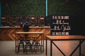 A bar area with a wooden counter, stools, and a sign with a quote.