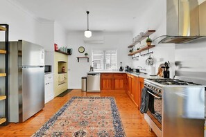 A modern kitchen with stainless steel appliances, wooden cabinets, and a patterned rug.