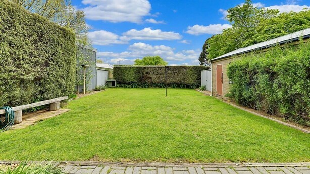 A backyard with a lawn, a wooden bench, and a hedge. - Oasis on Warrendine - Pet Friendly + Close to CBD (Orange)