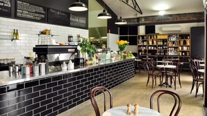 A restaurant with a black-tiled bar area, wooden chairs, and a ceiling fan. - Oasis on Warrendine - Pet Friendly + Close to CBD (Orange)