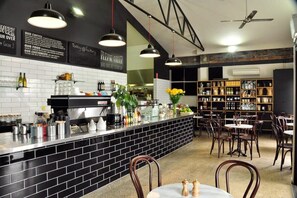 A restaurant with a black-tiled bar area, wooden chairs, and a ceiling fan.