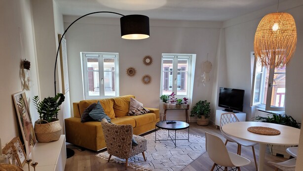 Un salon moderne avec un canapé jaune, une table ronde et un téléviseur.