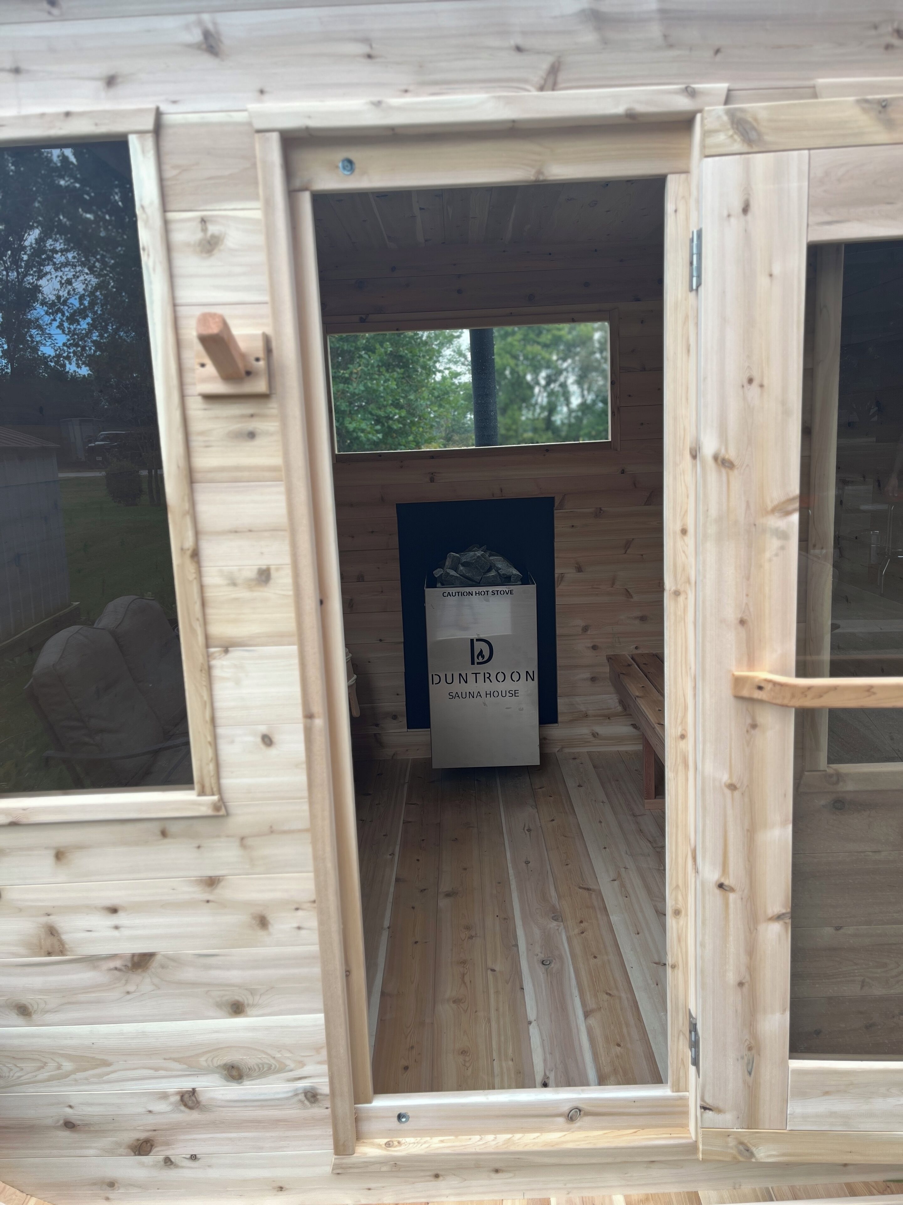 Un sauna avec un panneau d’avertissement, des murs en bois et une fenêtre.