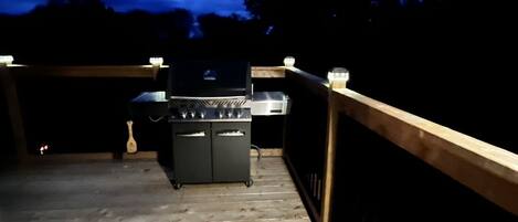 A wooden deck with a barbecue grill and a small table.