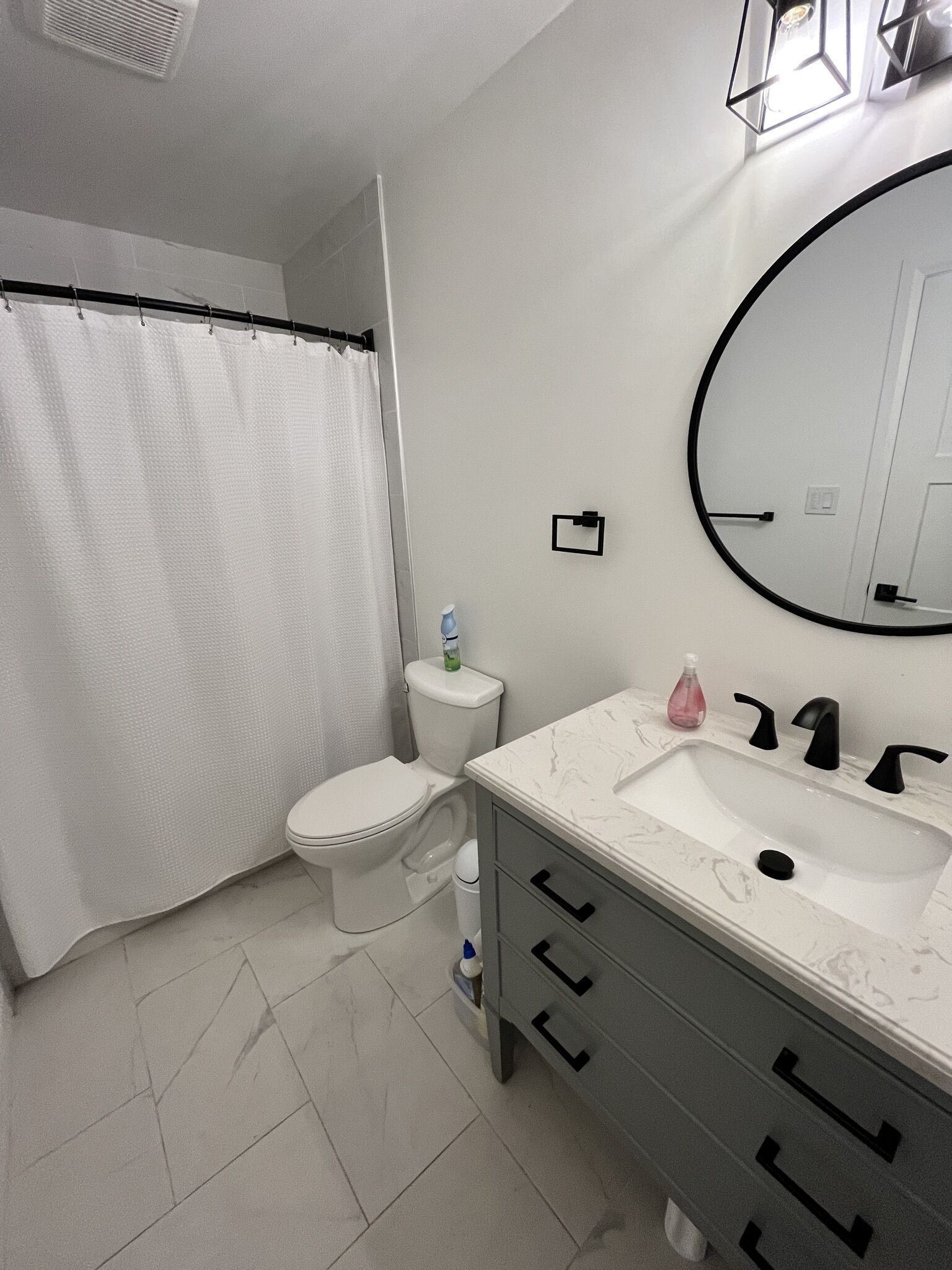 A bathroom with a toilet, a sink, a mirror, and a shower curtain.