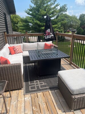 A deck with a sectional sofa, a table, and wicker furniture.