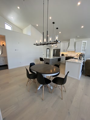 Contemporary kitchen with stove and sink, round dining table, and stainless steel appliances.