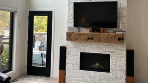 Ein modernes Wohnzimmer mit Kamin aus Stein, einem wandmontierten Flachbildfernseher und einem Ledersessel.