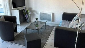 En moderne stue med fjernsyn, pejs, sofa og sofabord.