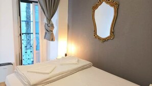 Une chambre d’hôtel avec un lit, une fenêtre avec des rideaux et un miroir au mur.
