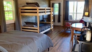 A room with a bunk bed, a desk with a lamp, and a kitchenette. - Large Cabin with Stunning View - Fire Pit, Relax & Unwind  (Gallipolis)