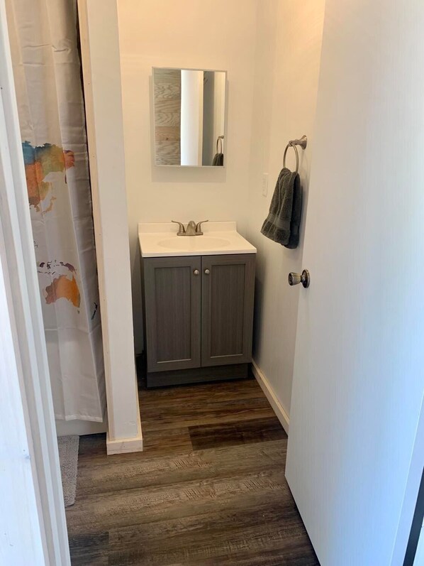 A bathroom with a white sink, dark wooden cabinets, a mirror above the sink, and a towel rack on the wall. - Large Cabin with Stunning View - Fire Pit, Relax & Unwind (Gallipolis)