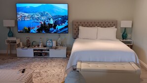 Une chambre moderne dotée d’une grande télévision, d’un lit, d’un canapé et d’une console sur laquelle sont disposés des objets décoratifs.