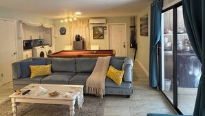 A living room with a sofa, coffee table, and a pool table.