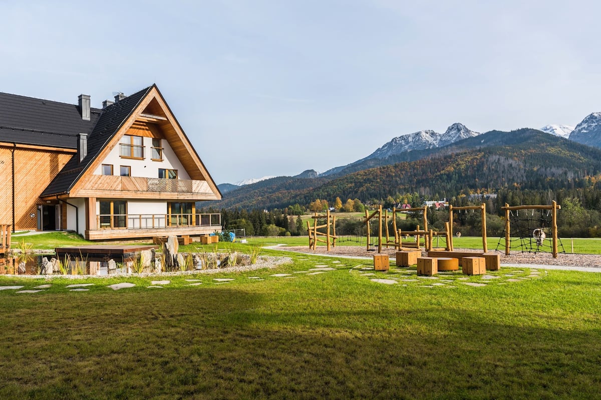 A modern house with a wooden deck and a view of mountains.