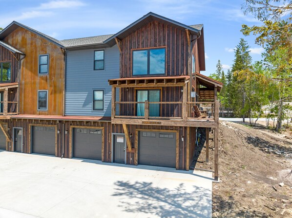 Une maison à deux étages avec une façade en bois, plusieurs portes de garage et un balcon.