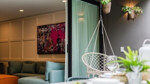 Een moderne woonkamer met een bank, een hangstoel en een tafel met een plant en een theepot.