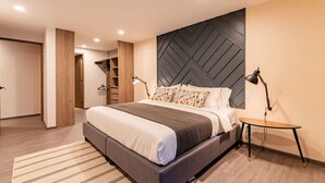 Een moderne slaapkamer met een groot bed, een inbouwkast en een bureau met een lamp.