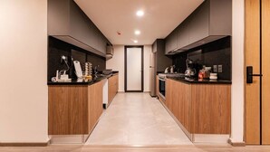 Cozinha moderna com armários de madeira, bancada preta e piso ladrilhado.