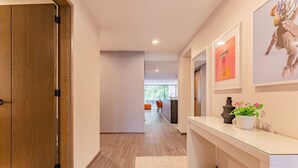 Ein moderner Flur mit Holztür, einer Rezeption und gerahmten Kunstwerken an der Wand.