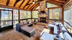 Un intérieur spacieux en bois, agrémenté d’une cheminée en pierre, de grandes fenêtres et d’un coin salon confortable.