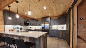 Une cuisine moderne dotée d’un îlot central, de tabourets de bar et d’appareils électroménagers intégrés.