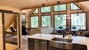 Une cuisine spacieuse dotée d’un grand îlot central, de murs en bois et de grandes fenêtres.