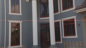 A building with multiple windows, white trim, and a tiled entrance. - MiGo House (Arusha)