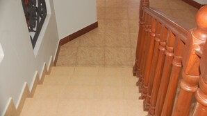 A staircase with wooden balusters and beige tiles. - MiGo House (Arusha)