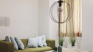 Un salón moderno con un sofá verde, una mesa de centro de madera y una ventana con cortinas a rayas.