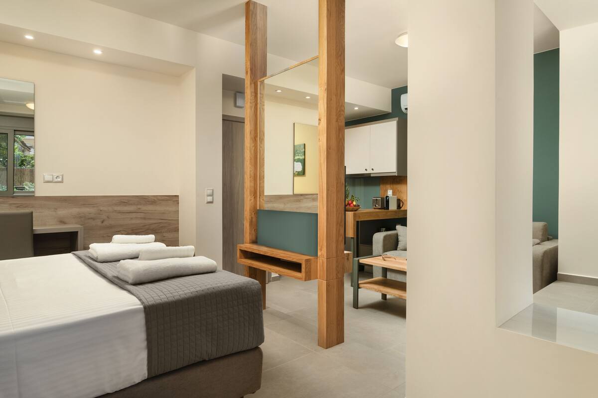 A modern hotel room with a large bed, a wooden desk, and a bathroom with a mirror and sink.