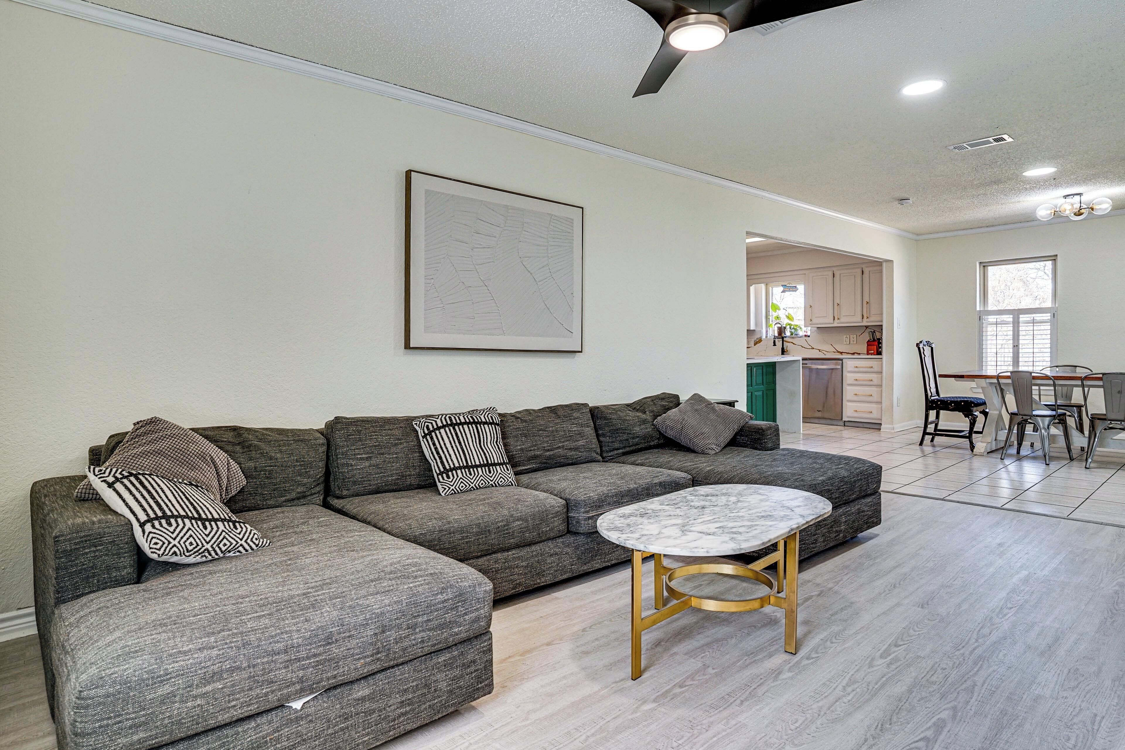 A modern living room with a sectional sofa, a round coffee table, and a dining area with chairs and a table.